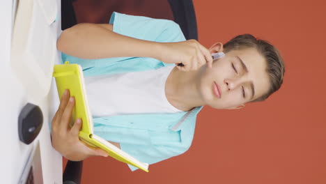 Vertical-video-of-Boy-with-notebook-thinks-and-takes-notes.